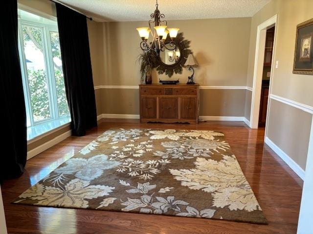 dining room featuring a textured ceiling, a notable chandelier, and wood-type flooring