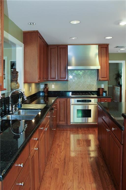 kitchen with dark stone counters, stainless steel microwave, light wood-type flooring, and a kitchen island