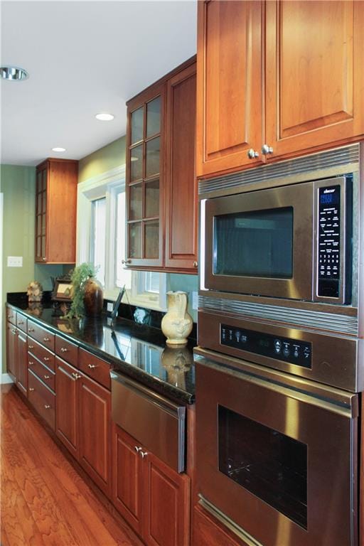 kitchen featuring dark stone countertops, light hardwood / wood-style floors, and stainless steel appliances