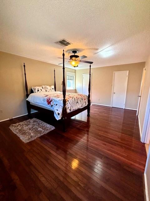 bedroom featuring dark hardwood / wood-style floors, a textured ceiling, and ceiling fan