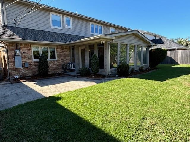 back of property featuring a patio, a sunroom, and a lawn