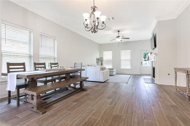 dining space featuring ceiling fan with notable chandelier, ornamental molding, and hardwood / wood-style floors