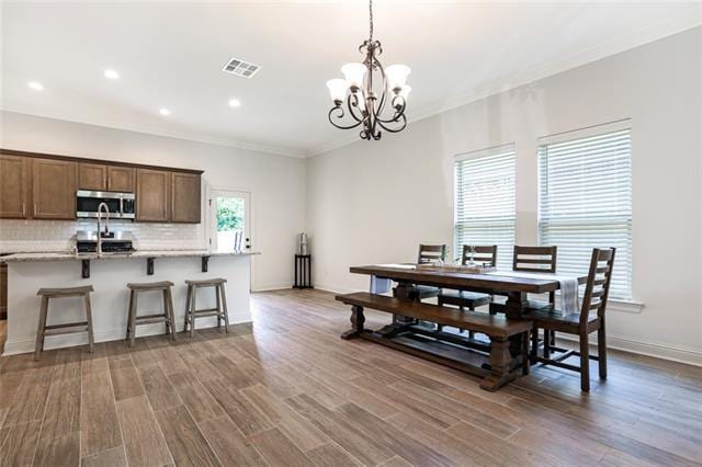 kitchen with a kitchen bar, tasteful backsplash, wood-type flooring, and pendant lighting