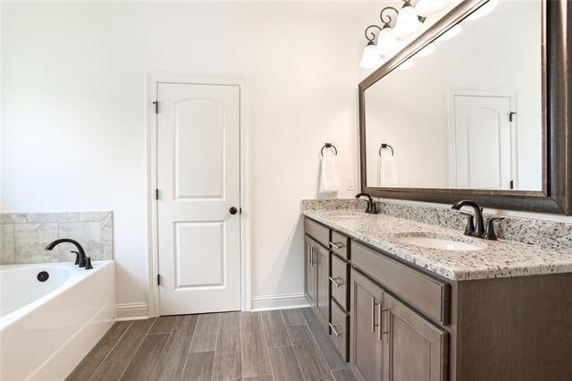 bathroom with a tub and dual vanity