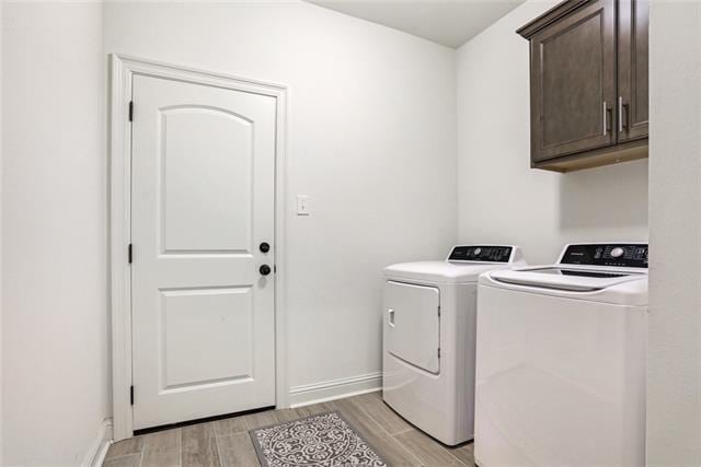 clothes washing area with cabinets, separate washer and dryer, and light hardwood / wood-style floors