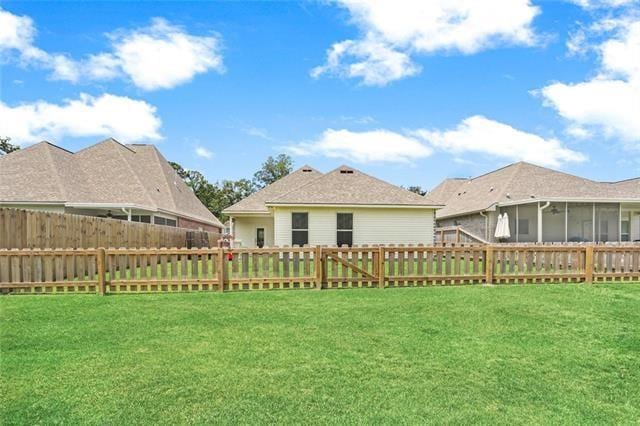 back of property featuring a sunroom and a lawn