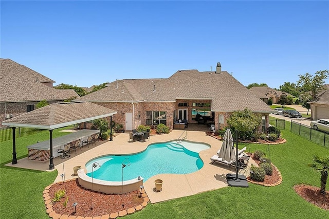 view of swimming pool featuring a bar, a patio area, and a lawn