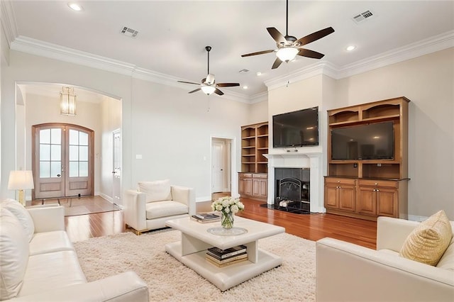 living room with crown molding, french doors, and light wood-type flooring