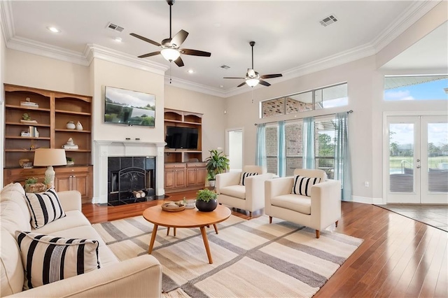 living room with a fireplace, french doors, light wood-type flooring, and ornamental molding