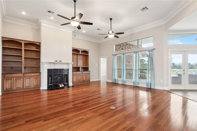 unfurnished living room with a tiled fireplace, french doors, and ornamental molding