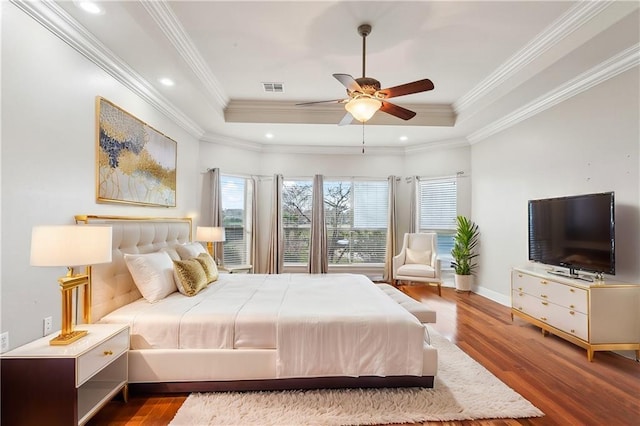 bedroom featuring ceiling fan, wood-type flooring, and a tray ceiling