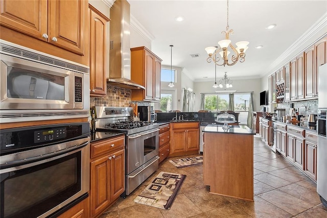 kitchen with a center island, stainless steel appliances, wall chimney range hood, a notable chandelier, and pendant lighting