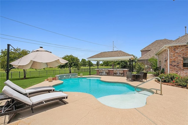 view of swimming pool with pool water feature, a patio, an outdoor kitchen, and a lawn