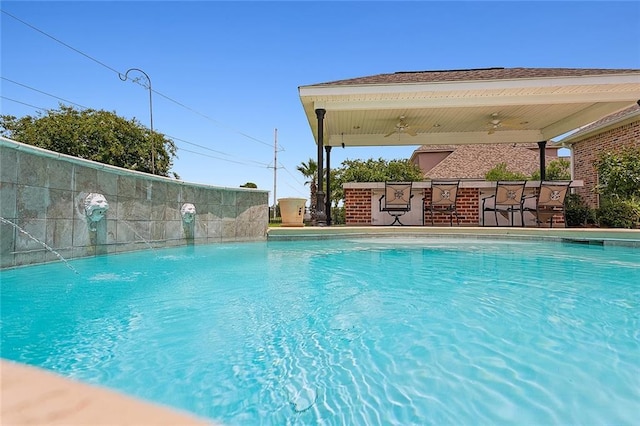 view of swimming pool with pool water feature and a bar