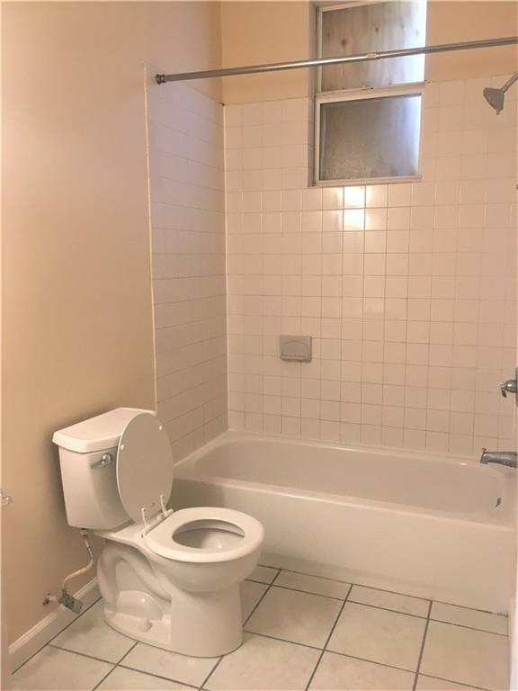 bathroom with tiled shower / bath combo, tile patterned floors, and toilet