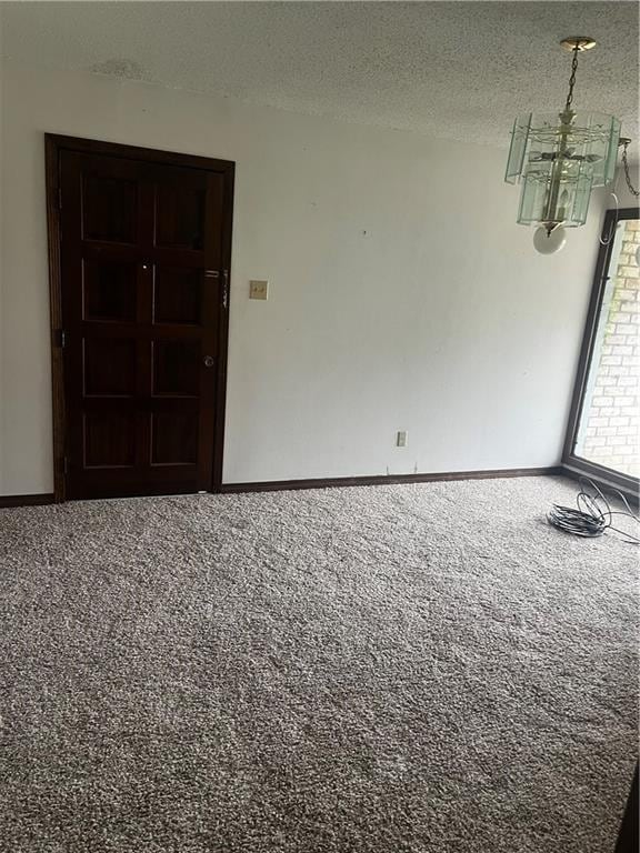 spare room with a notable chandelier, carpet, and a textured ceiling