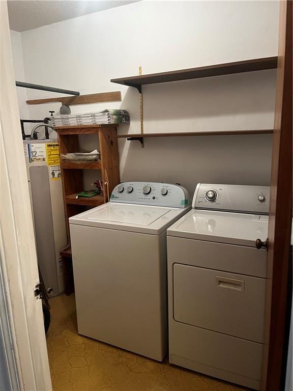 washroom with washing machine and clothes dryer and water heater