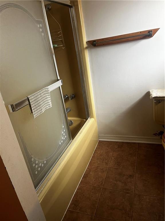 bathroom with tile patterned floors and shower / bath combination with glass door