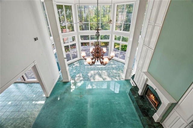 interior space with a tile fireplace, a towering ceiling, an inviting chandelier, and dark tile patterned flooring