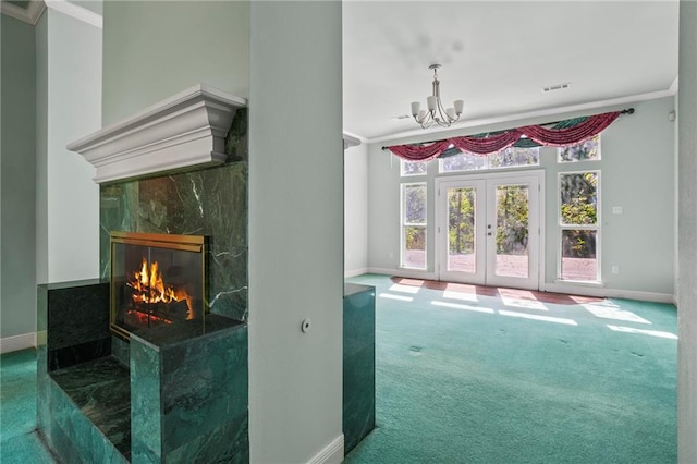 carpeted living room with ornamental molding, an inviting chandelier, a premium fireplace, and french doors