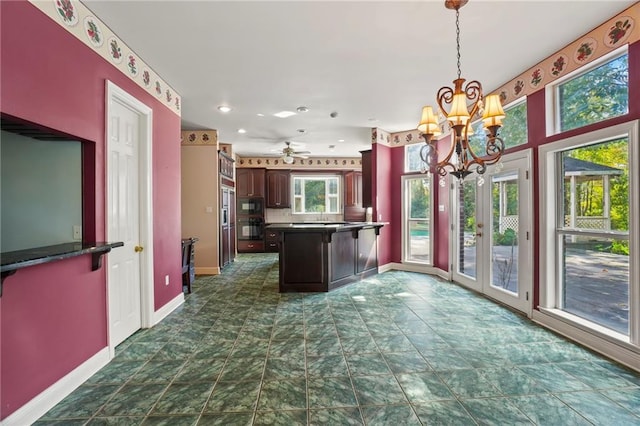 kitchen featuring dark tile patterned flooring, dark brown cabinets, ceiling fan with notable chandelier, black microwave, and decorative light fixtures