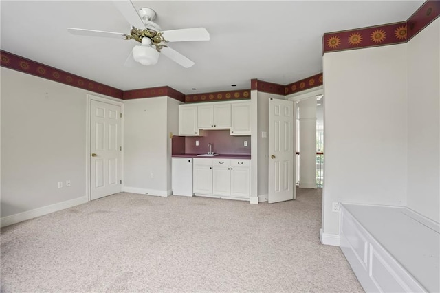 30 River Cypress Ln, Madisonville, LA 70447 - kitchen with light colored carpet, baseboards, white cabinets, a sink, and a ceiling fan