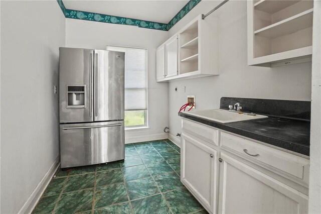 kitchen with stainless steel refrigerator with ice dispenser, sink, and white cabinetry