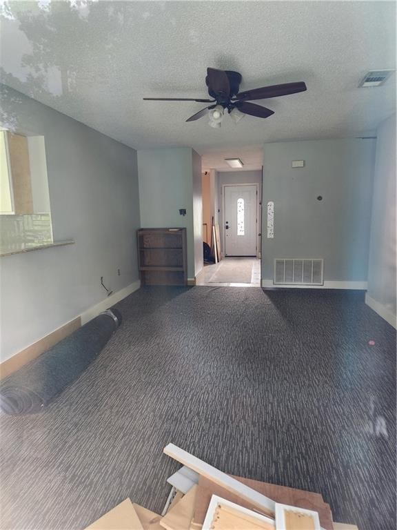 interior space with a textured ceiling, carpet floors, and ceiling fan