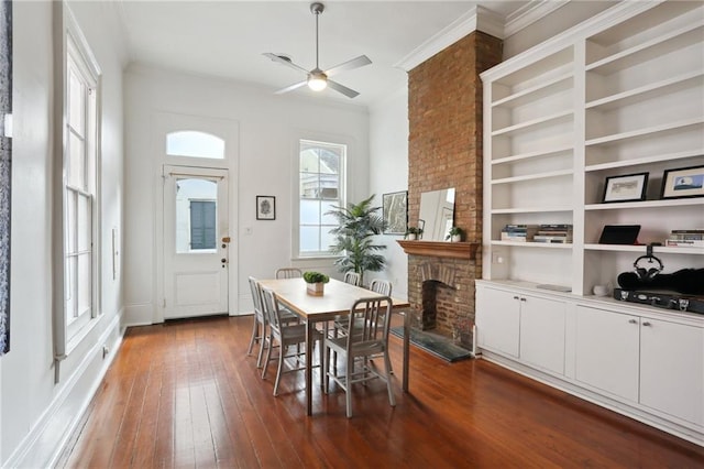 dining room featuring ceiling fan, dark wood-type flooring, built in features, a fireplace, and ornamental molding