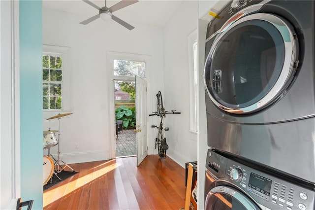 clothes washing area with stacked washing maching and dryer, hardwood / wood-style flooring, and ceiling fan