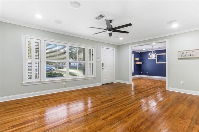 unfurnished living room featuring ornamental molding, ceiling fan with notable chandelier, and hardwood / wood-style flooring