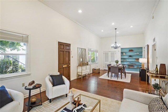 living room featuring a notable chandelier, built in shelves, hardwood / wood-style flooring, and plenty of natural light