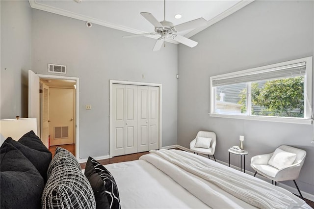 bedroom with a closet, a high ceiling, crown molding, ceiling fan, and wood-type flooring