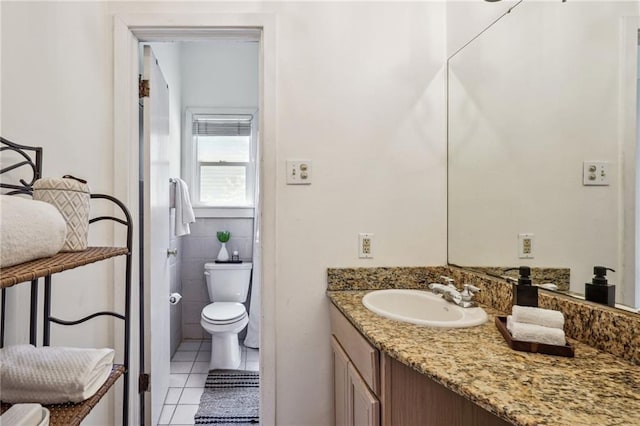 bathroom with vanity, toilet, tile patterned floors, and tile walls