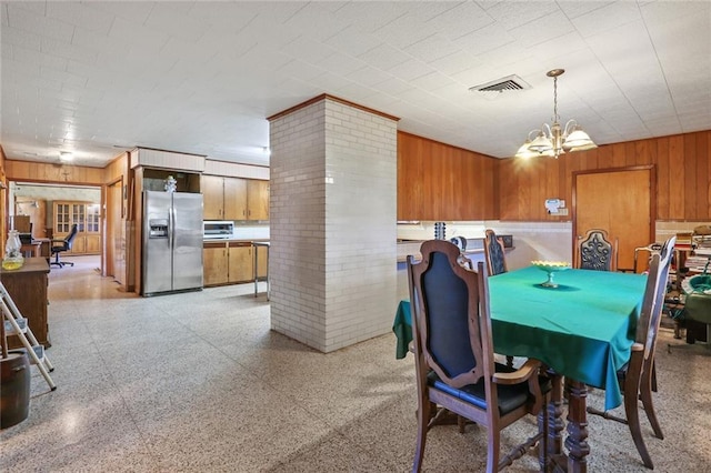 dining space featuring a notable chandelier and wood walls