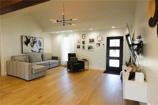 living room featuring vaulted ceiling with beams, a notable chandelier, and light hardwood / wood-style floors