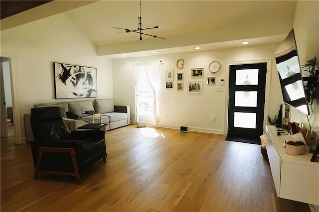 living room with hardwood / wood-style flooring, a notable chandelier, and lofted ceiling