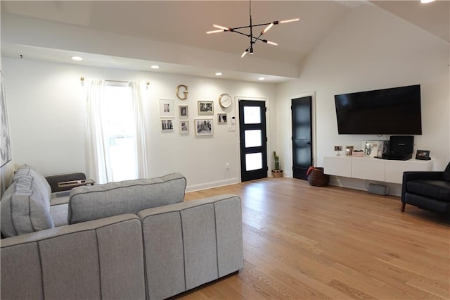 living room with lofted ceiling, hardwood / wood-style floors, an inviting chandelier, and a healthy amount of sunlight