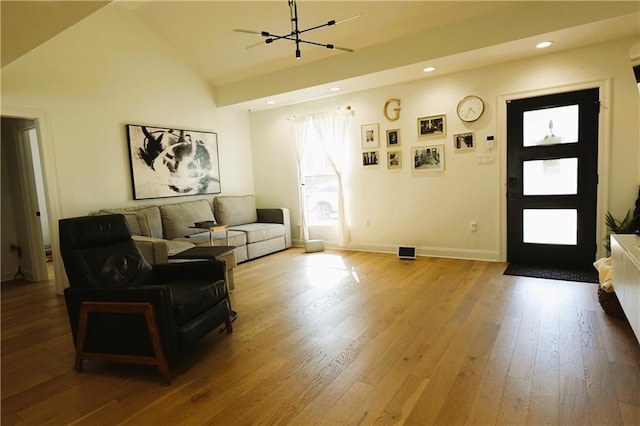 living room with hardwood / wood-style flooring, vaulted ceiling, and a notable chandelier