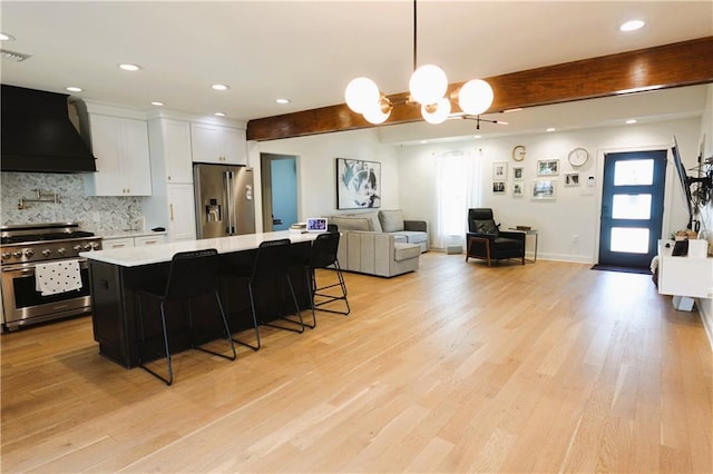 kitchen featuring premium range hood, white cabinetry, a center island, appliances with stainless steel finishes, and a kitchen breakfast bar