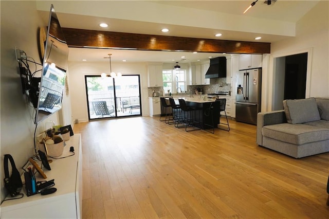 kitchen with a kitchen island, appliances with stainless steel finishes, wall chimney range hood, and white cabinets