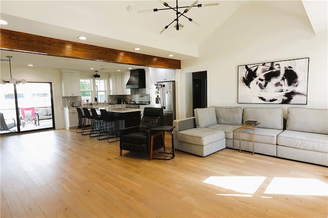 living room with an inviting chandelier, light hardwood / wood-style flooring, high vaulted ceiling, and beamed ceiling