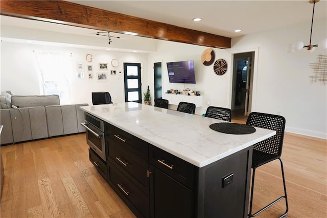 kitchen featuring a kitchen bar, a center island, light hardwood / wood-style floors, and hanging light fixtures