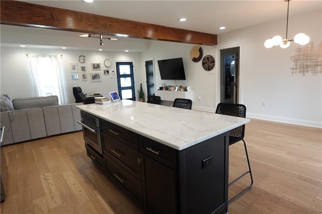 kitchen featuring hanging light fixtures, a kitchen breakfast bar, beamed ceiling, and a kitchen island