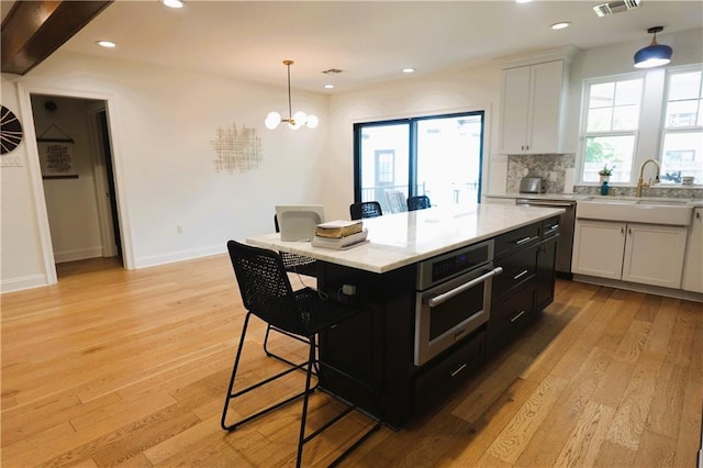 kitchen with sink, decorative light fixtures, appliances with stainless steel finishes, a kitchen island, and white cabinets