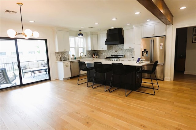 kitchen featuring decorative light fixtures, custom exhaust hood, stainless steel appliances, and white cabinets