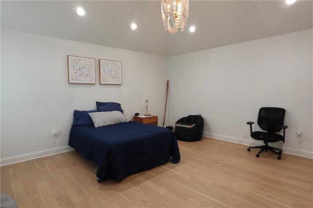 bedroom with an inviting chandelier, light hardwood / wood-style flooring, and lofted ceiling