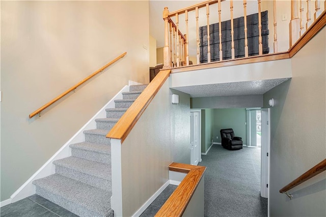 staircase with carpet floors and a textured ceiling