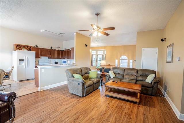 living room with light hardwood / wood-style flooring, ceiling fan, and a textured ceiling