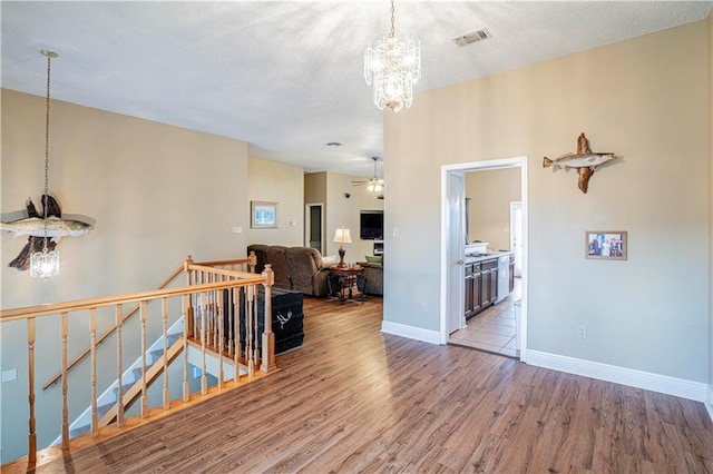 hallway featuring an inviting chandelier, light hardwood / wood-style floors, and a textured ceiling